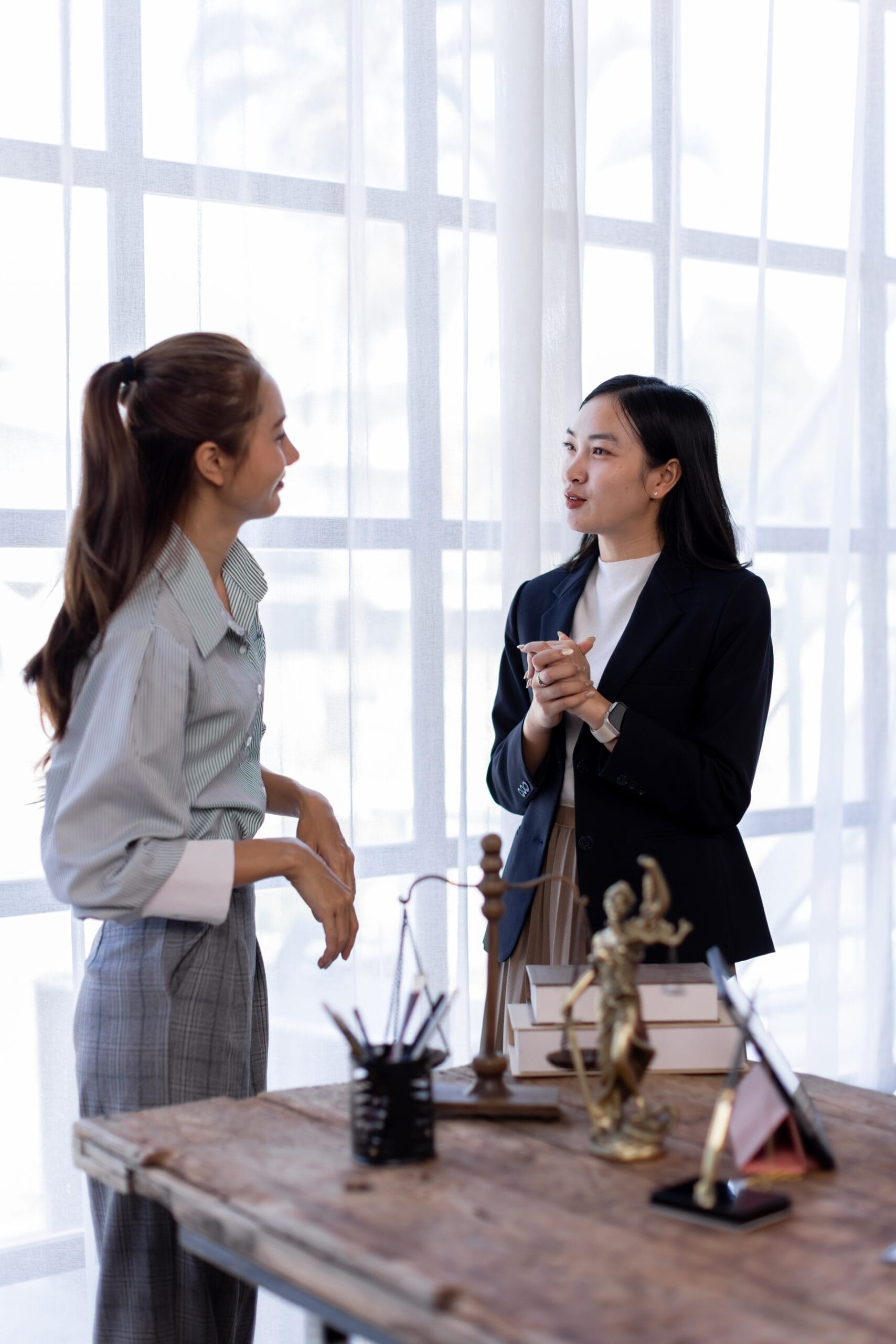 Female lawyer talking with client in office giving legal advice and consultation with justice statue on desk