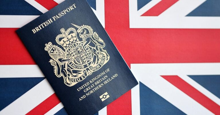Blue British passport lying on a Union Jack flag