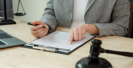 Solicitor reviewing an employment contract on a clipboard, with a gavel on the desk