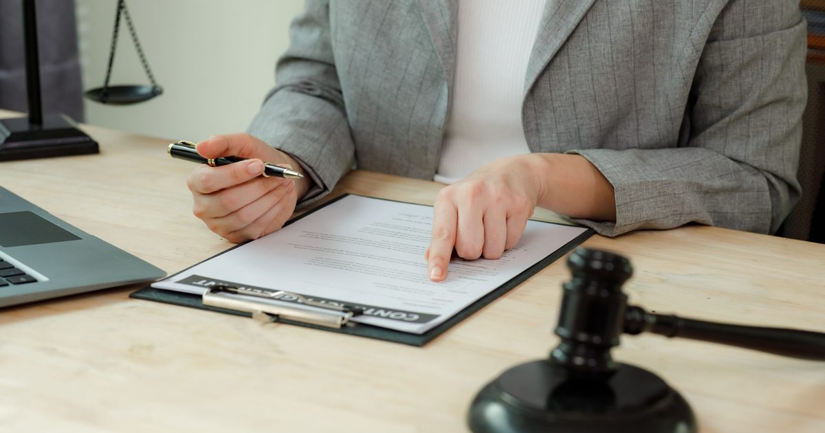 Solicitor reviewing an employment contract on a clipboard, with a gavel on the desk